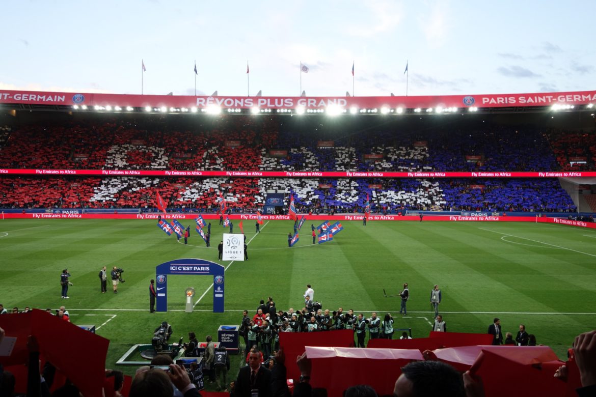 Estadio del PSG con los futbolistas a punto de saltar, las gradas con los colores del equipo: rojo y azul y en blanco la palabra París