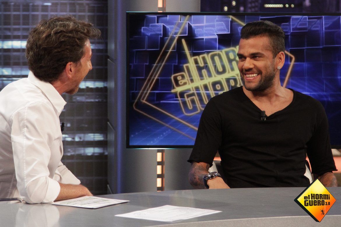 Dani Alves en el programa de entretenimiento El Hormiguero, vestido de negro, junto al presentador Pablo Motos, con su camisa blanca, en el año 2014