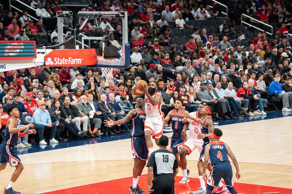 James Harden saltando para encestar el balón, vestido con la equipación blanca de los Rockets