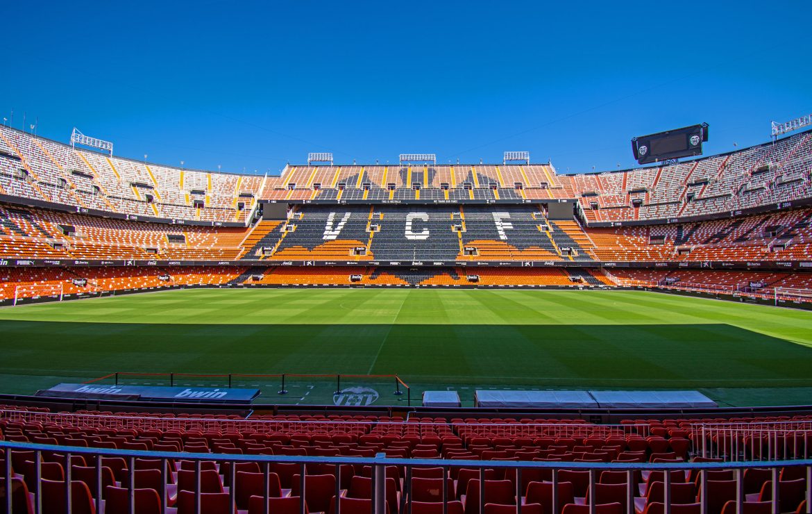 Mestalla, el estadio del Valencia con el césped y las gradas con el murciélago en negro y las iniciales del club: VCF